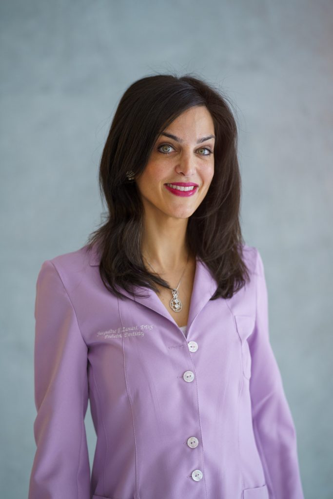 Dr. Zamani of Sky Dental--pediatric dentist NYC--smiles, wears a purple dentist coat.