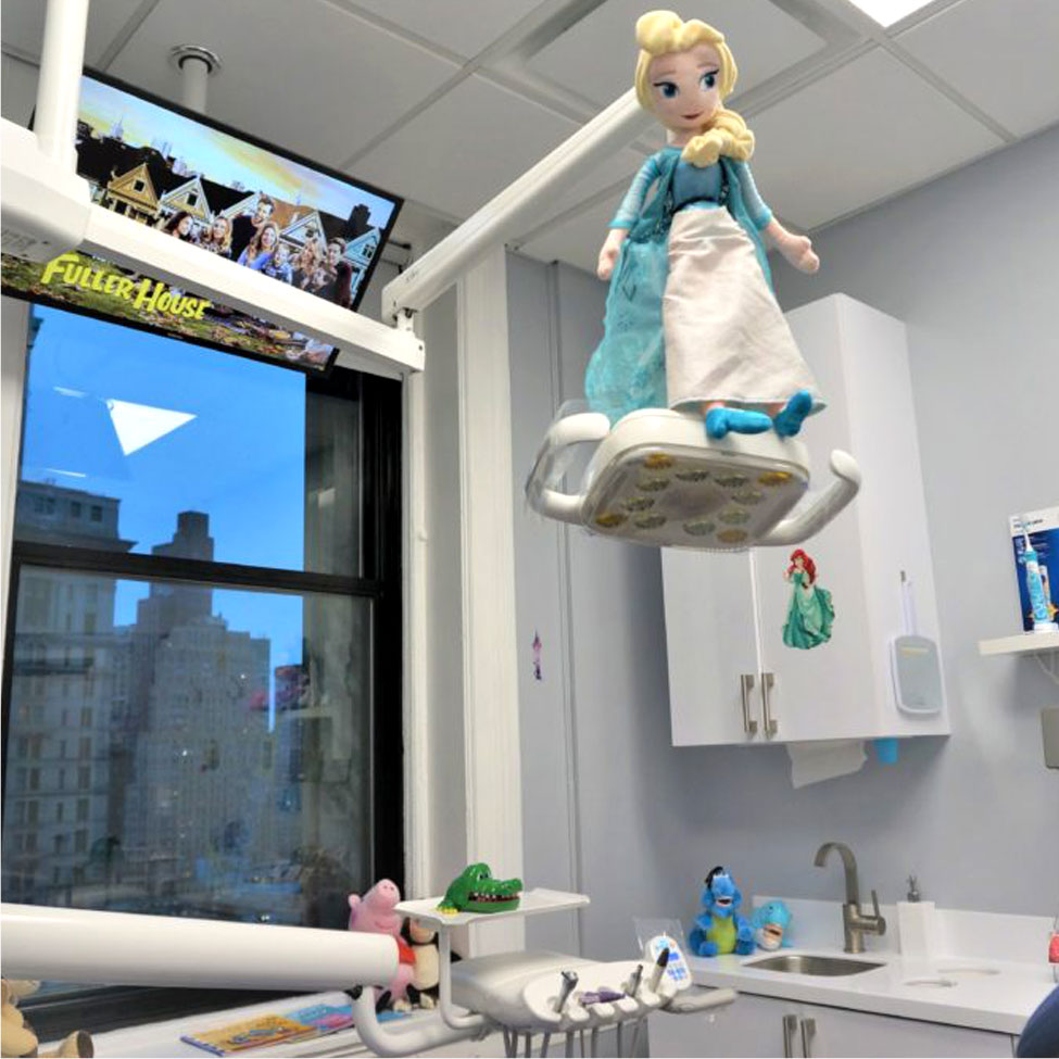Kids exam room: Elsa doll above chair, Fuller House on TV, Little Mermaid on cabinet, stuffed animals placed here and there.