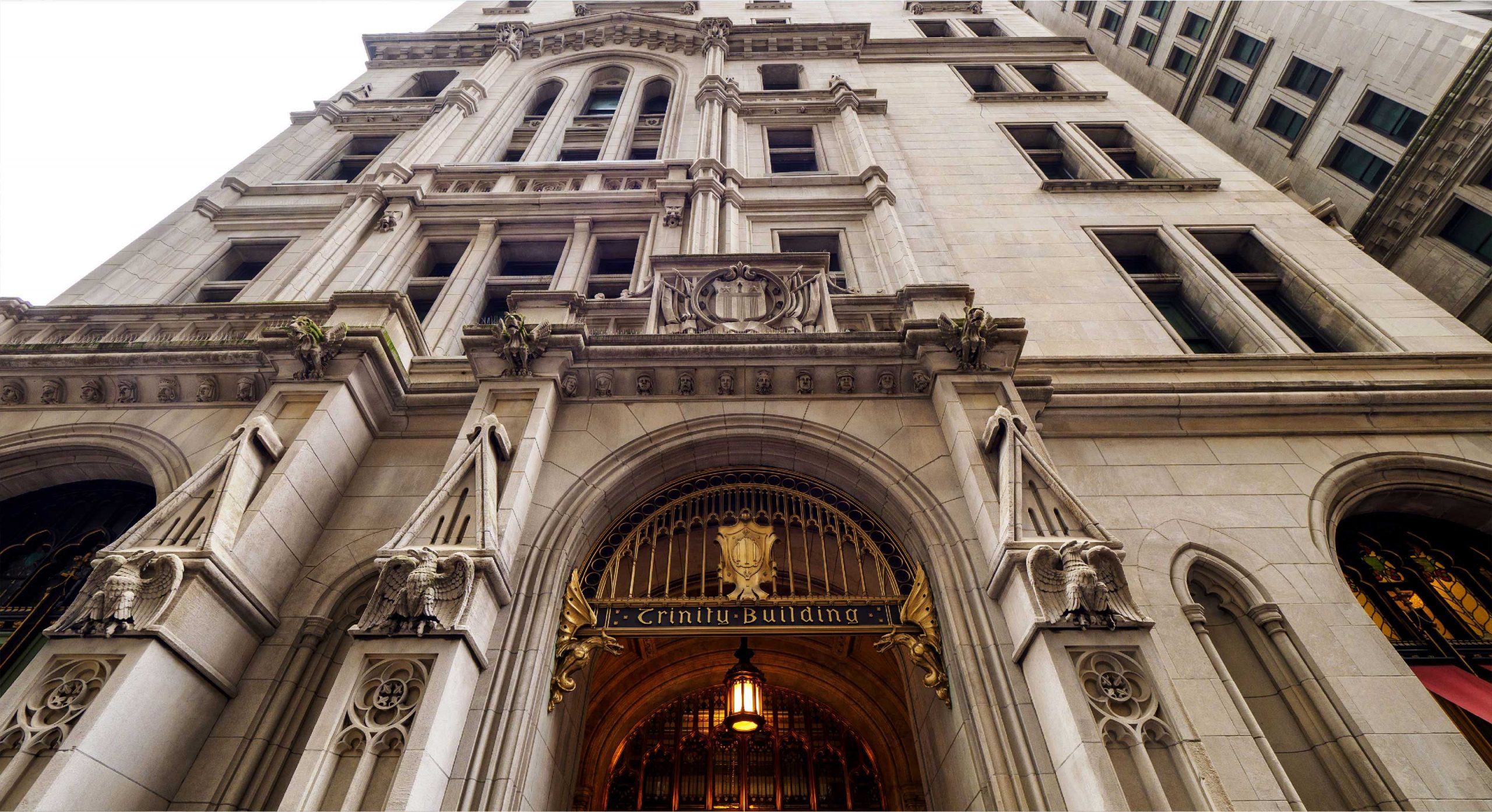 Entrance to Sky Dental NYC, the best dentist in FiDi NYC. The Trinity Building is gothic, built with sandstone blocks. Gargoyles, dragons, etc. flank the grand, golden entrance.