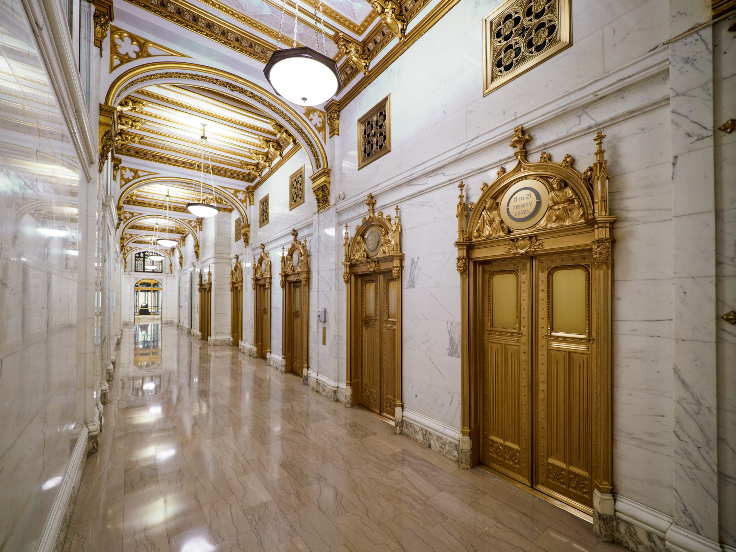 Ornate marble hallway inside the Trinity Building; doors, fixtures, and crown moulding are painted gold.