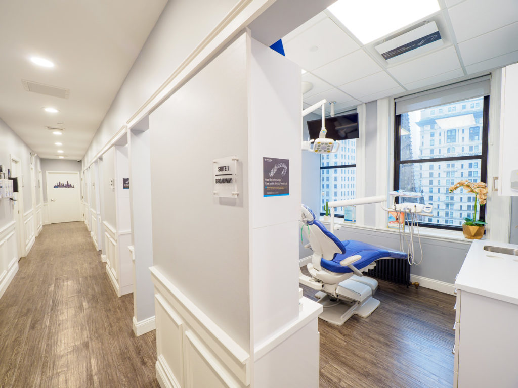 A Sky Dental treatment room; bright, white, clean, attractive city view. Sign on the wall reads, "Suite 1: Broadway."