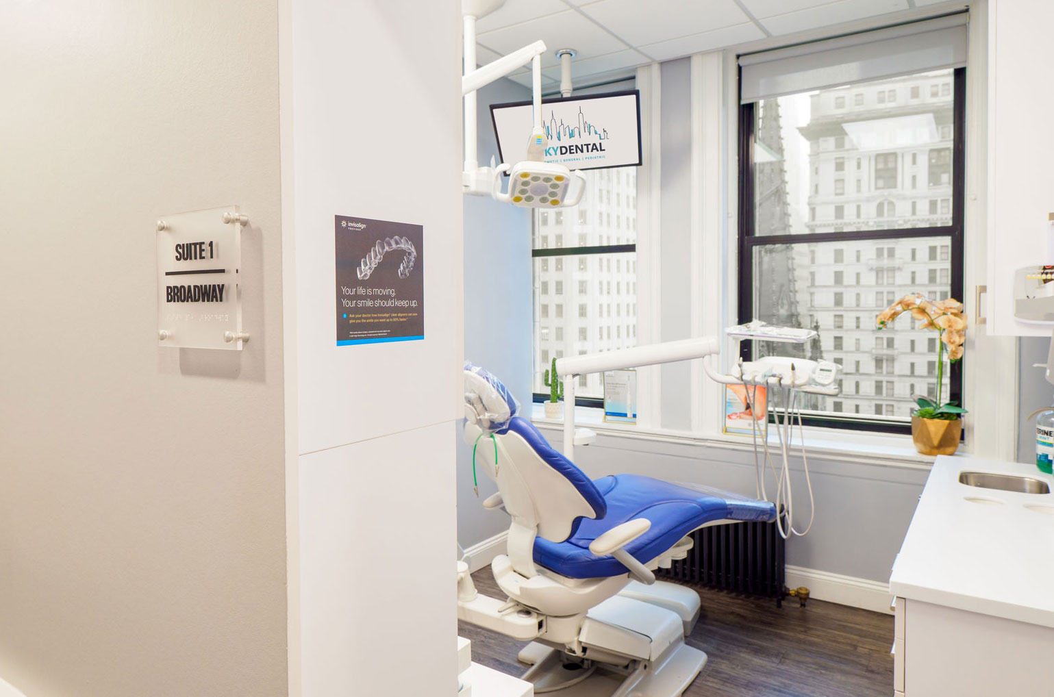 A Sky Dental treatment room; bright, white, clean, attractive city view. Sign on the wall reads, 