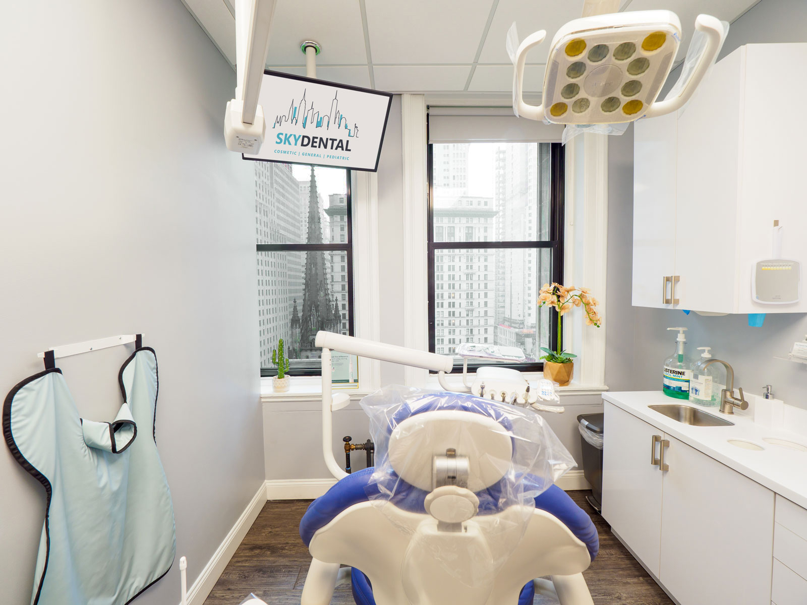 Clean, bright, white exam room, treatment chair at Sky Dental NYC, windows looking out to gorgeous city view.