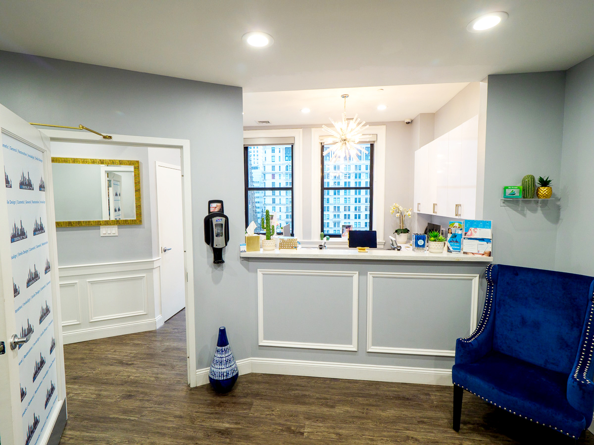 NYC dentist office Sky Dental's lobby. Clean gray-and-white interior with royal blue velvet furniture, brightly lit.
