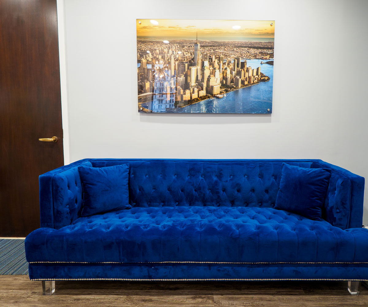 Sky Dental in NYC's FiDi: Waiting room couch is royal blue velvet; above it hangs a golden-hour photograph of the NYC skyline.