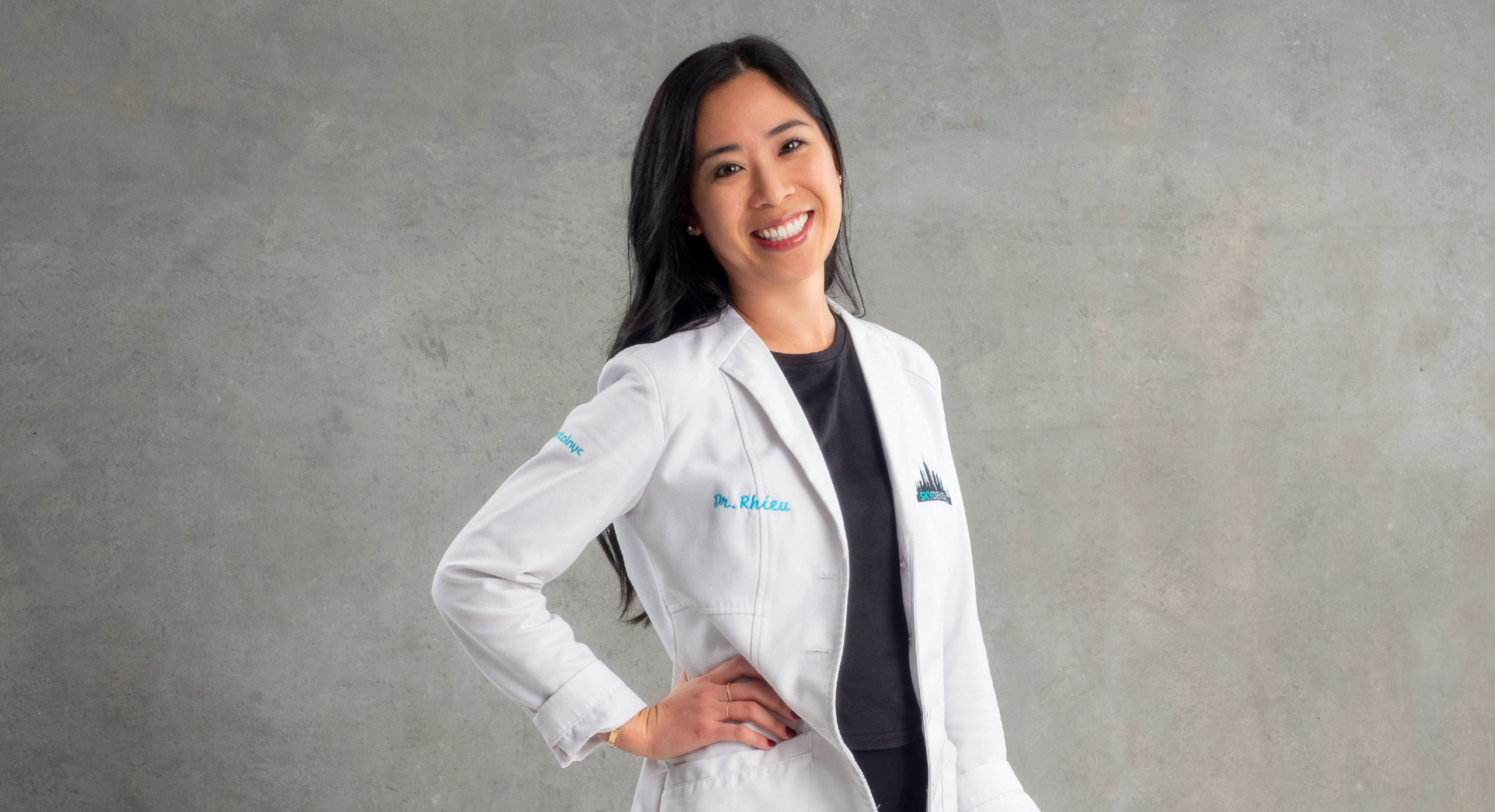 Dr. Wonnie Rhieu, founder of Sky Dental NYC, smiling, hand on hip. Dr. Rhieu is a cosmetic and general dentist.