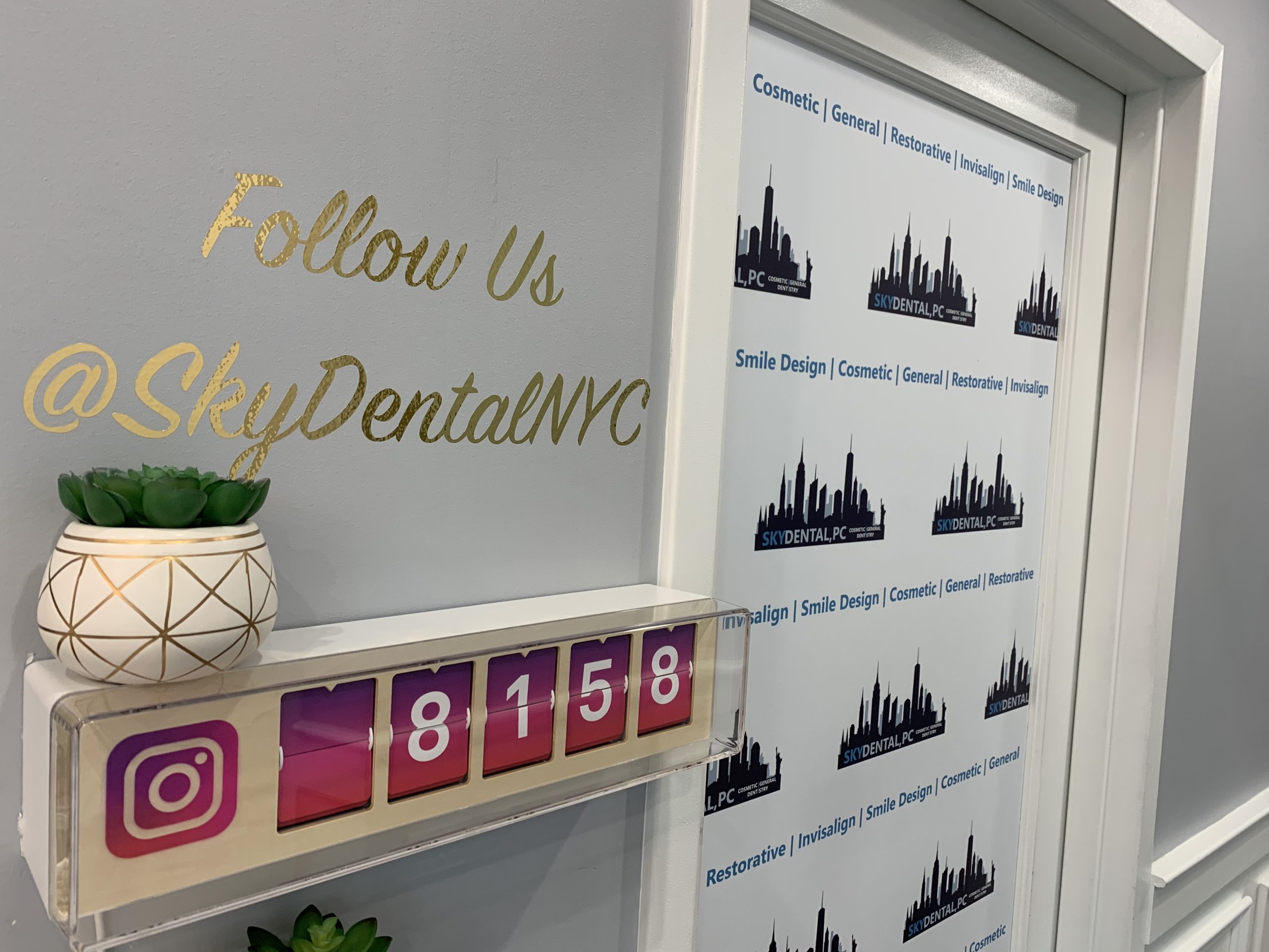 Sky Dental Instagram follower counter hangs on a wall in the office. It reads 8158. Above it on the wall, 