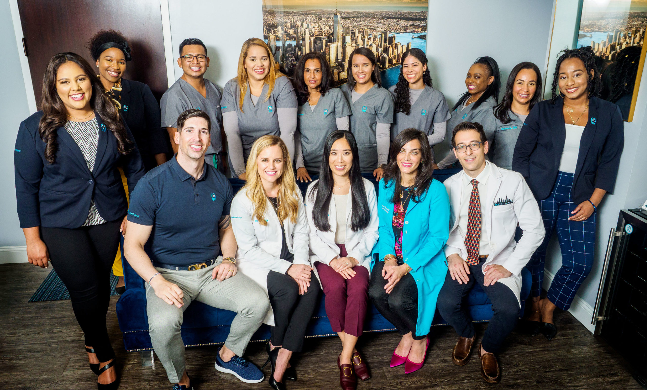 Sky Dental NYC team poses together indoors, doctors and Mark seated, hygienists and assistants standing behind them.