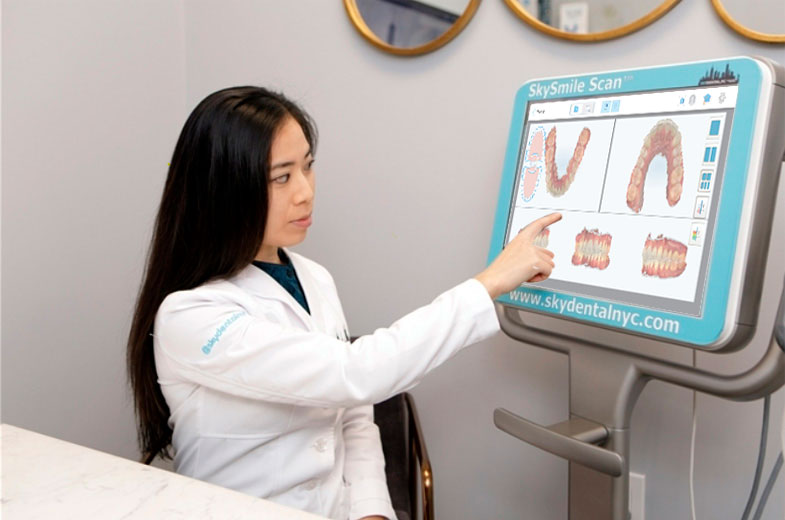 Dentist points to an image of a patient's teeth on Sky Dental's Smile Scan NYC monitor.