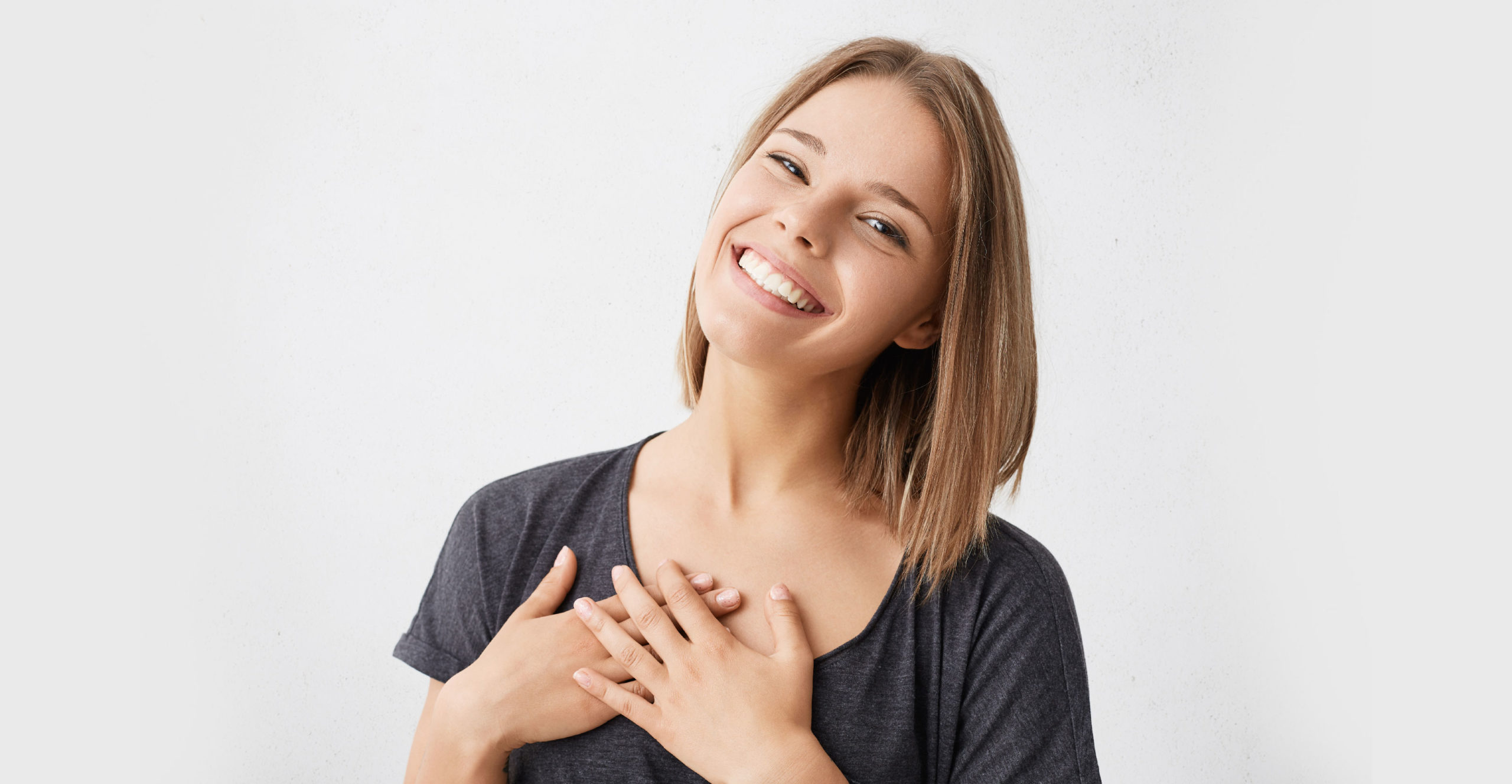 Woman smiles, hands on heart.