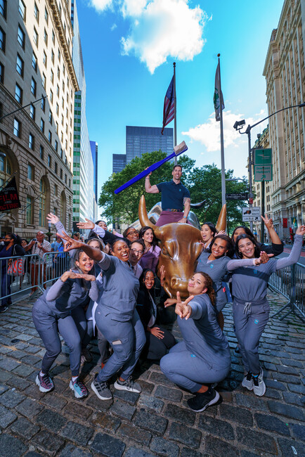 Sky Dental team poses enthusiastically on and around the Wall Street Bull sculpture. Mark holds a comically oversized toothbrush.